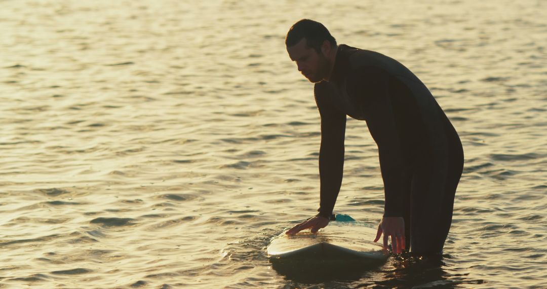 Surfer preparing for session in evening sunlight - Free Images, Stock Photos and Pictures on Pikwizard.com