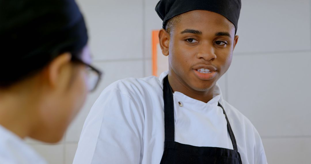 Young Black Chef Engaging in Conversation in Professional Kitchen - Free Images, Stock Photos and Pictures on Pikwizard.com