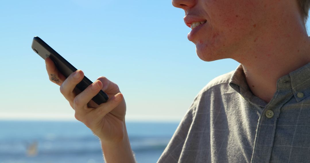 Close-up of Young Man Using Voice Command on Smartphone at Beach - Free Images, Stock Photos and Pictures on Pikwizard.com