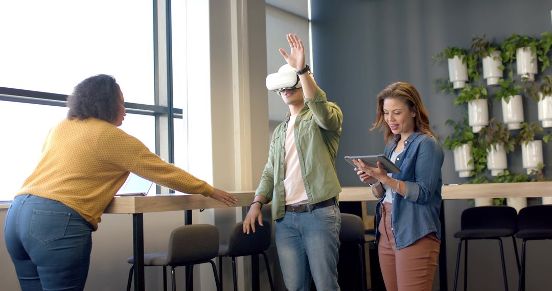 Diverse team collaborating with virtual reality headset and tablet in modern office lounge