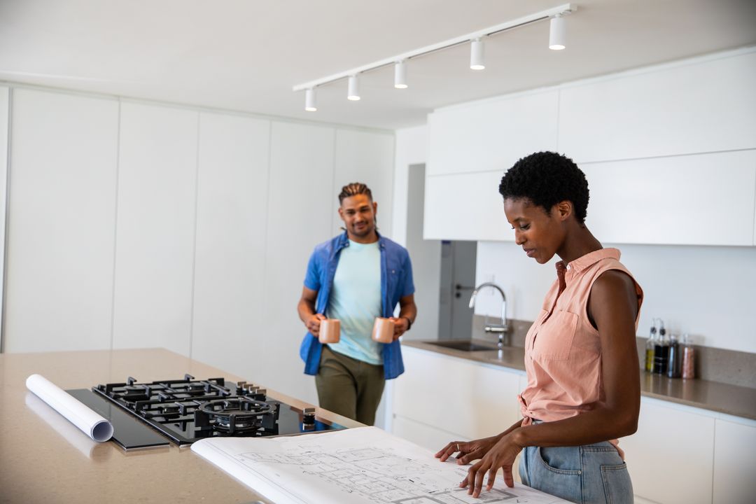 Couple Collaborating with Blueprints in Modern Kitchen Design