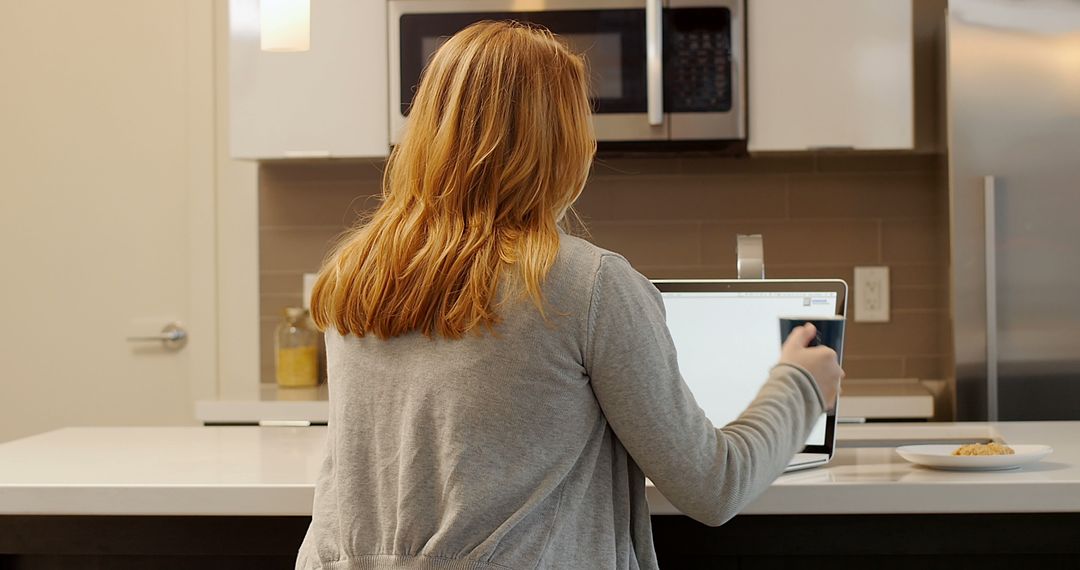 Woman Working on Laptop in Modern Kitchen Environment - Free Images, Stock Photos and Pictures on Pikwizard.com