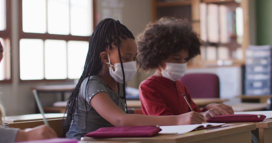 Diverse Schoolchildren Wearing Masks and Writing in Classroom - Free Images, Stock Photos and Pictures on Pikwizard.com