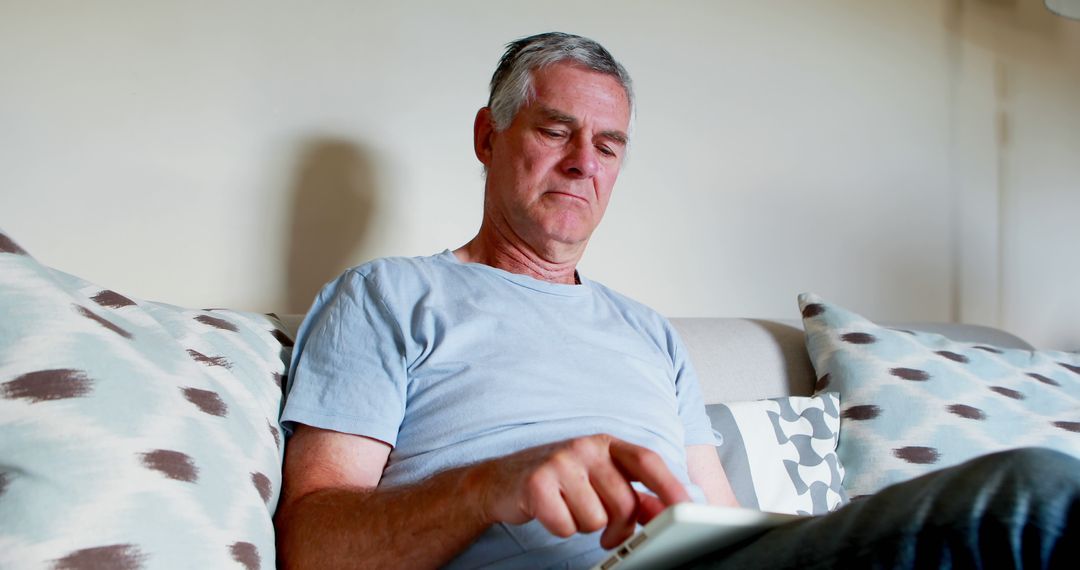 Senior Man Using Tablet Device on Comfortable Couch - Free Images, Stock Photos and Pictures on Pikwizard.com