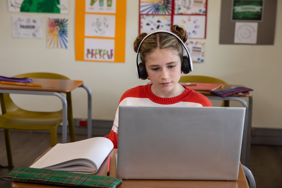 Focused Student Using Laptop with Headphones in Classroom Setting