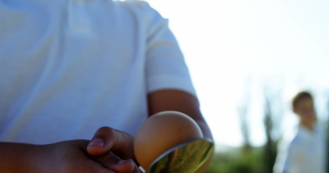 Child Holding Spoon with Egg Outdoors during Fun Activity - Free Images, Stock Photos and Pictures on Pikwizard.com