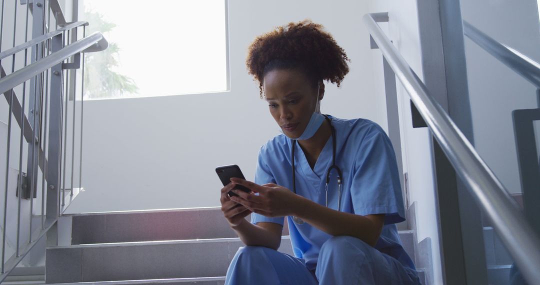 Nurse Taking a Break on Stairwell Checking Phone in Hospital Setting - Free Images, Stock Photos and Pictures on Pikwizard.com