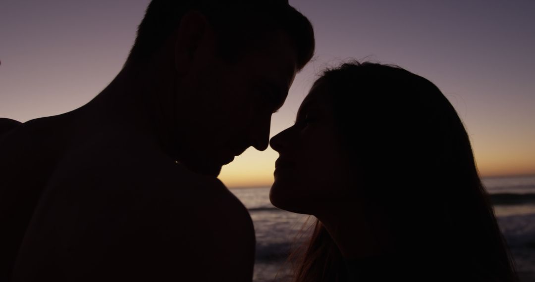 Silhouetted Couple Sharing Intimate Moment at Sunset Beach - Free Images, Stock Photos and Pictures on Pikwizard.com