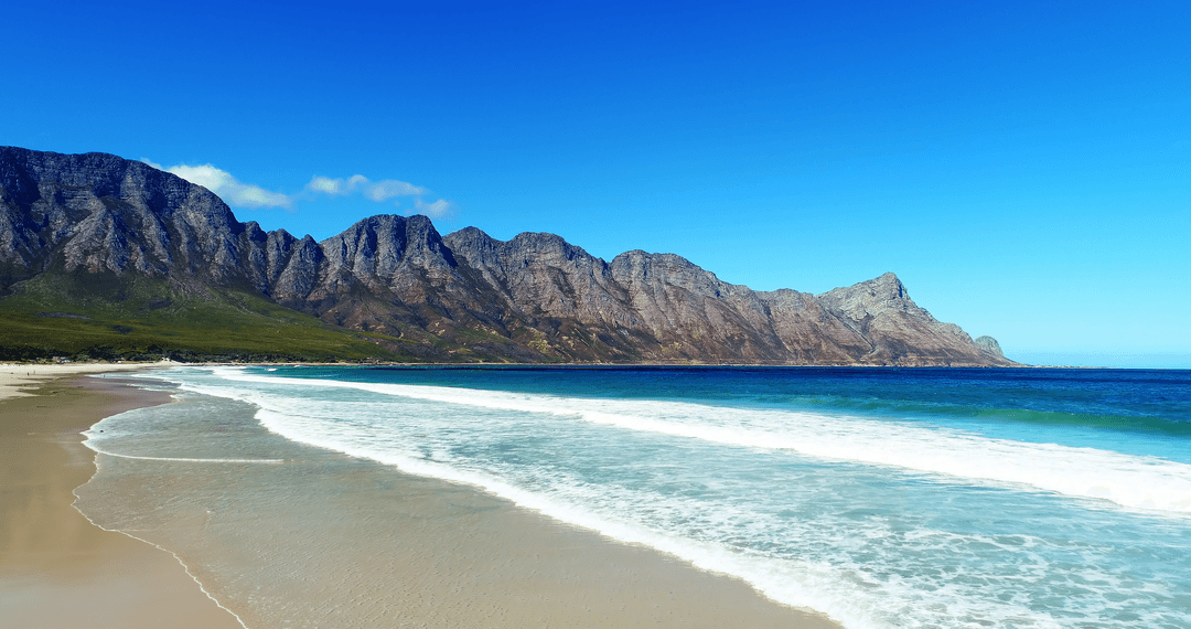 Transparent Waves Gently Caressing Coastal Mountains Under Blue Sky