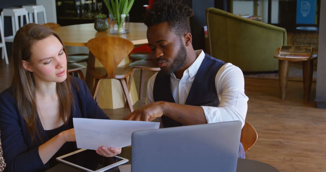 Diverse Colleagues Analyzing Business Report in Modern Café