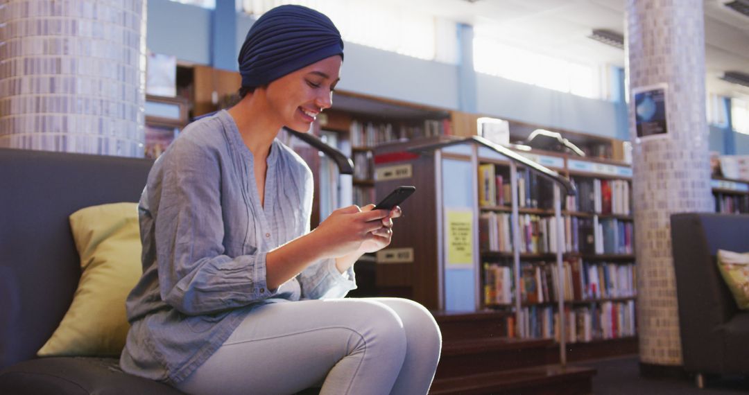 Smiling Woman Browsing Smartphone in Cozy Library Setting - Free Images, Stock Photos and Pictures on Pikwizard.com