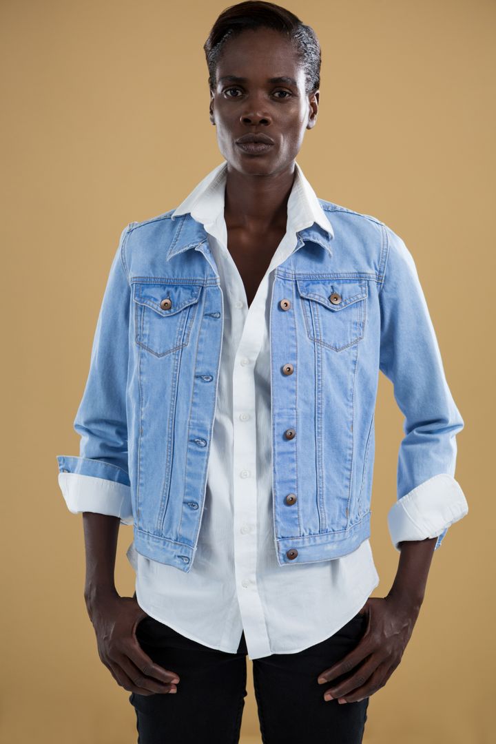 Androgynous man in denim jacket posing against beige background - Free Images, Stock Photos and Pictures on Pikwizard.com
