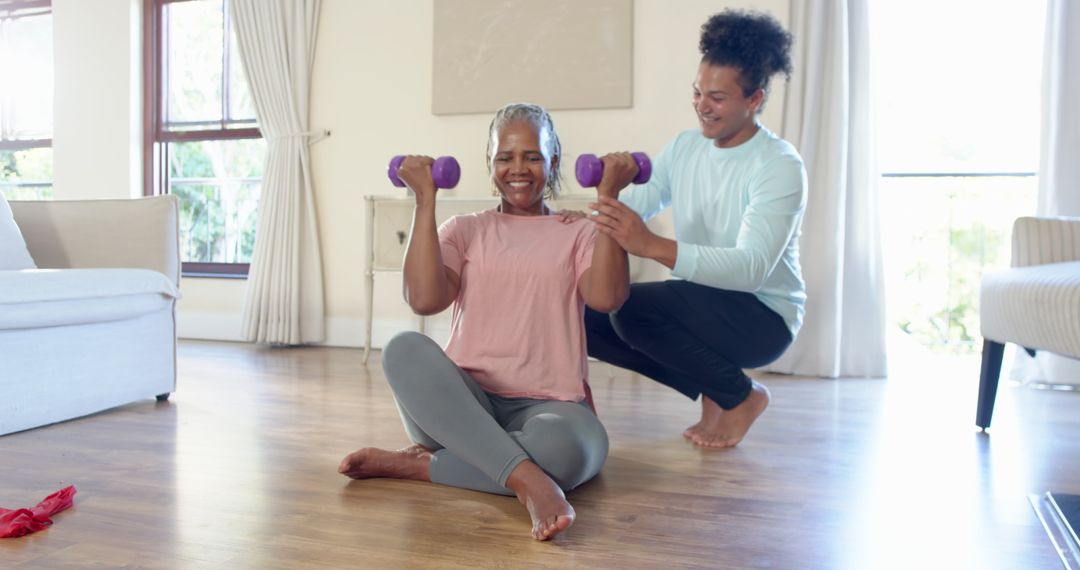 Senior Woman Exercising with Dumbbells and Personal Trainer at Home