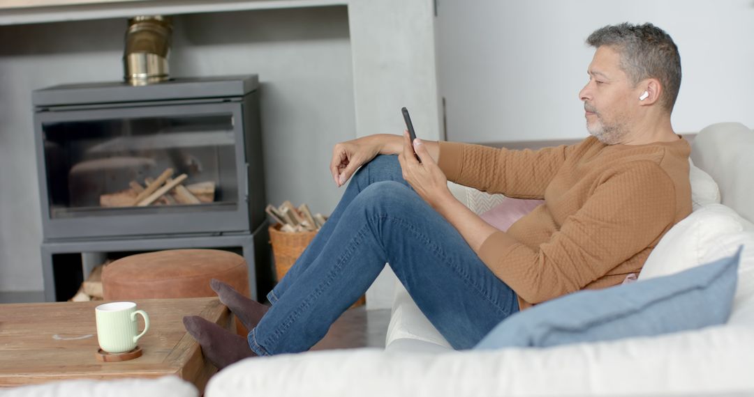 Middle-aged Man Relaxing with Smartphone by Fireplace - Free Images, Stock Photos and Pictures on Pikwizard.com