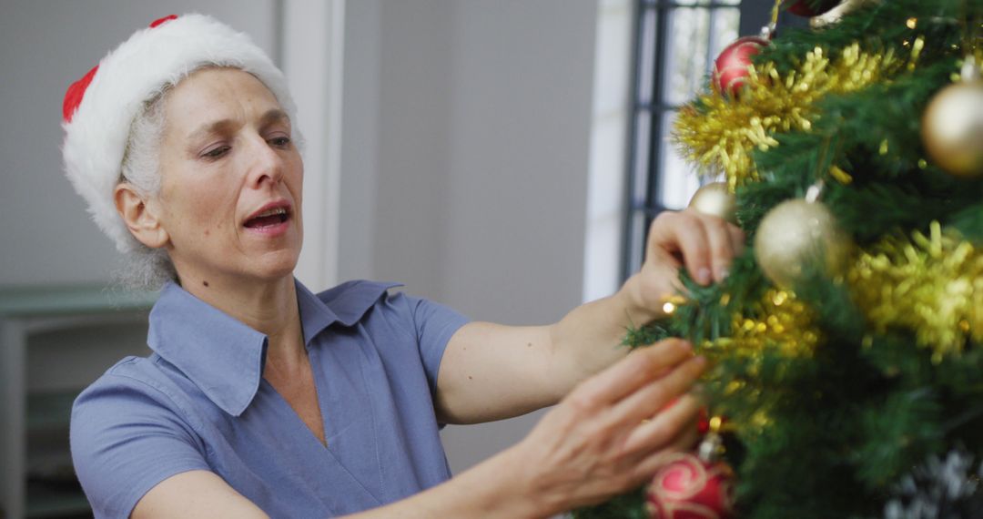 Senior Woman Decorating Christmas Tree with Festive Ornaments - Free Images, Stock Photos and Pictures on Pikwizard.com