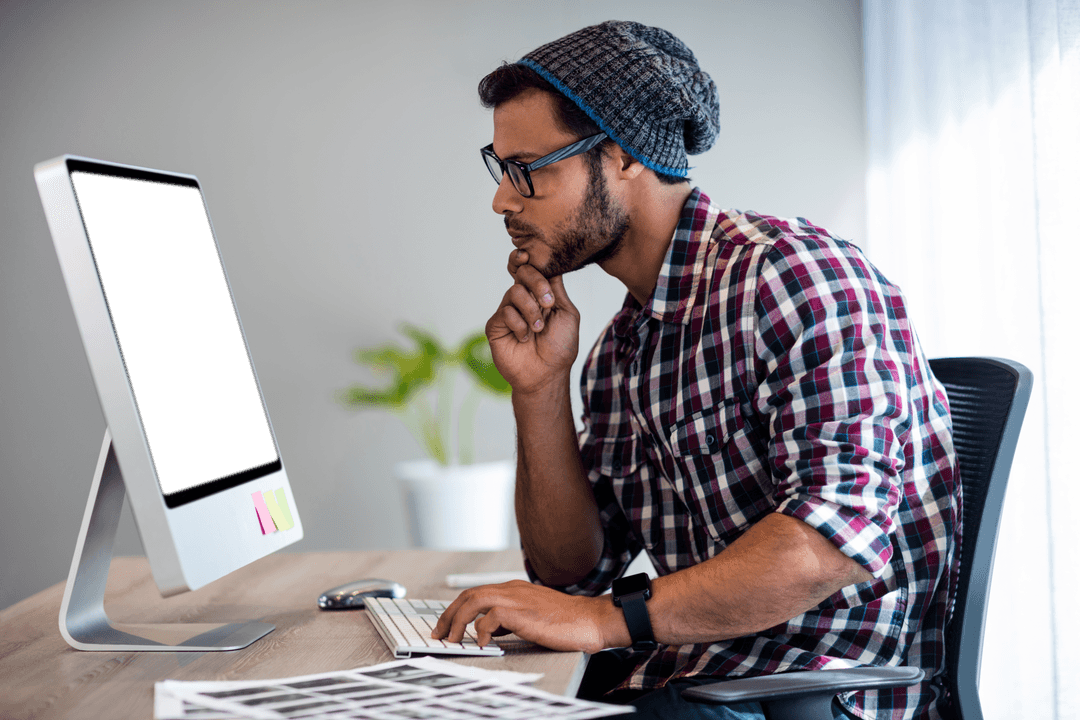 Concentrated Man Analyzing Computer Monitor in Office Setting
