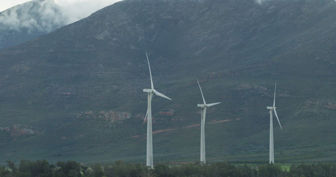 General view of wind turbines in countryside landscape with mountains - Free Images, Stock Photos and Pictures on Pikwizard.com