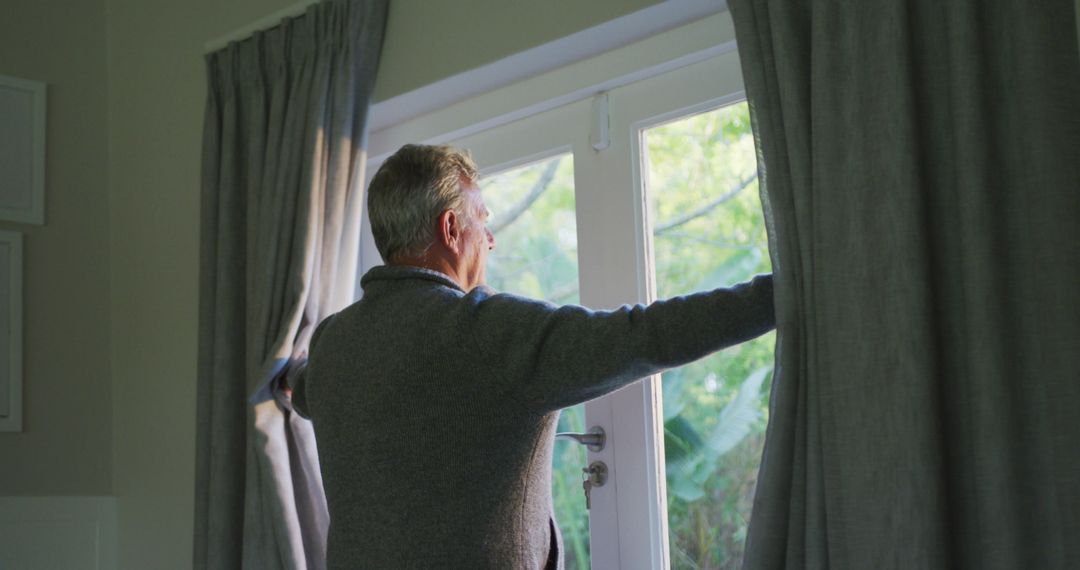 Senior Man Opening Curtains to Let in Morning Light - Free Images, Stock Photos and Pictures on Pikwizard.com