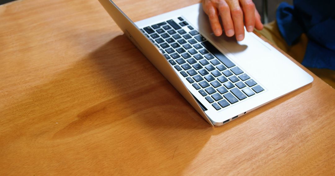 Person Using Laptop on Wooden Desk