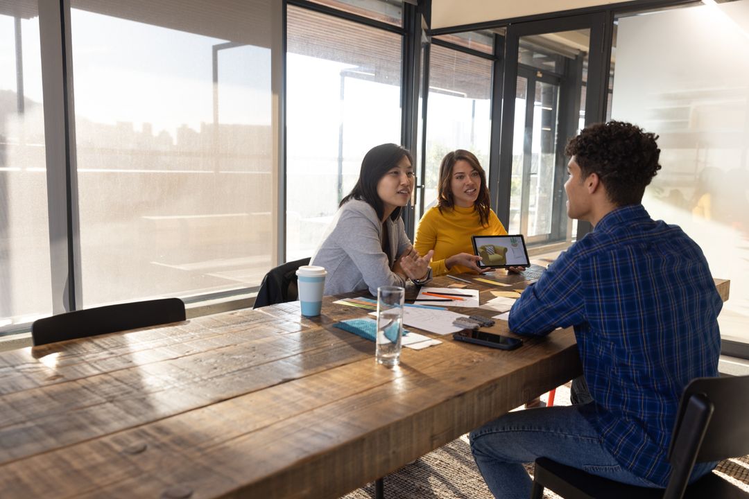 Diverse Team in Office Collaborating Around Table with Tablet Discussion