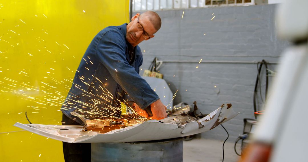 Male mechanic using grinder in workshop with sparks flying - Free Images, Stock Photos and Pictures on Pikwizard.com