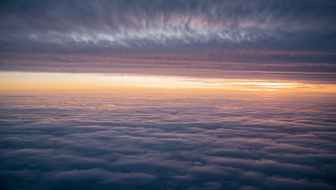 Aerial View of Sunrise Above Clouds and Layered Sky