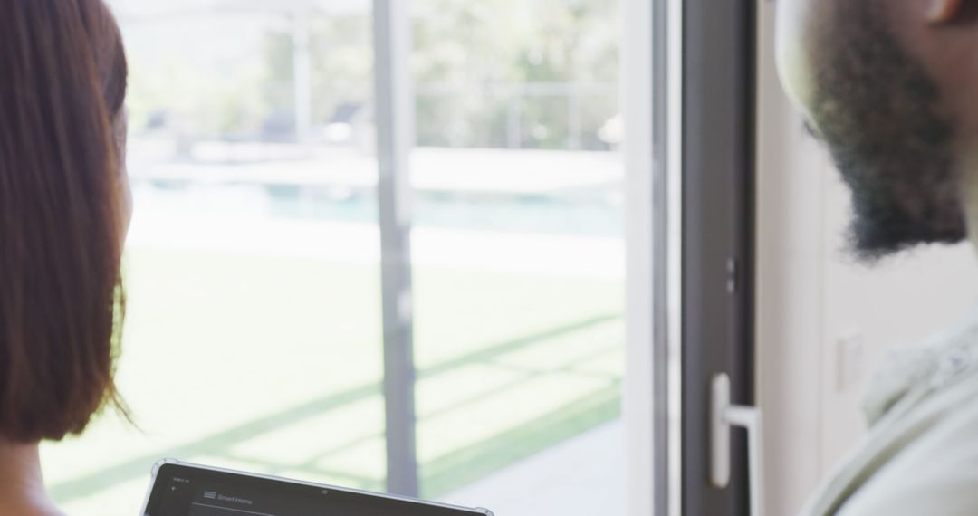Couple Using Tablet by Sunlit Window at Home