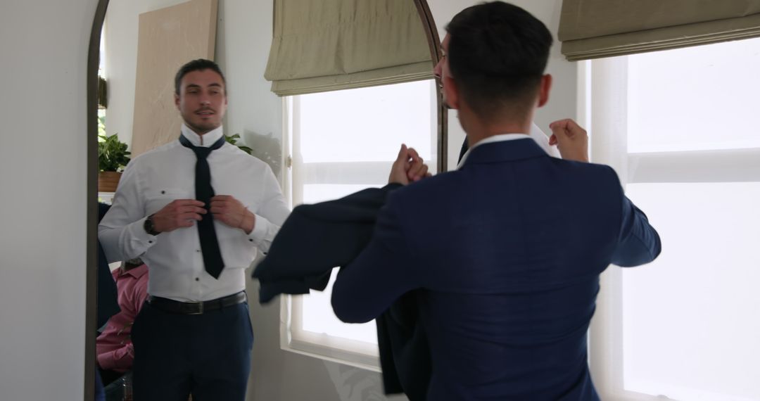Groom Adjusting Tie in Mirror Before Wedding