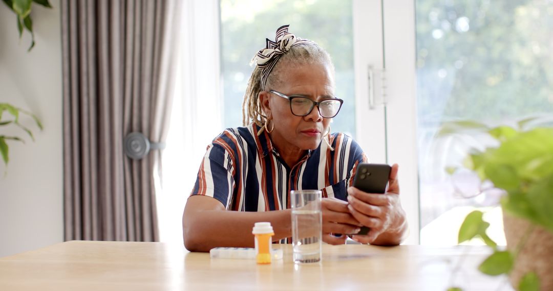 Senior Woman Using Smartphone with Medicine Bottles on Table
