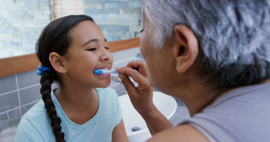 Hispanic Daughter Getting Teeth Brushed by Elderly Grandfather in Bathroom - Free Images, Stock Photos and Pictures on Pikwizard.com