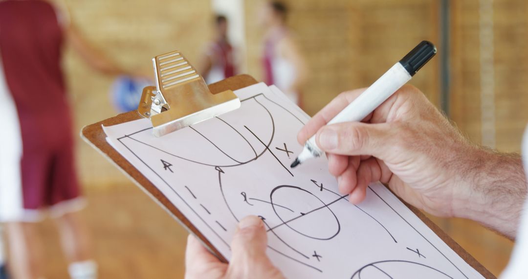 Hands of basketball coach drawing diagram on clipboard in the basketball court - Free Images, Stock Photos and Pictures on Pikwizard.com