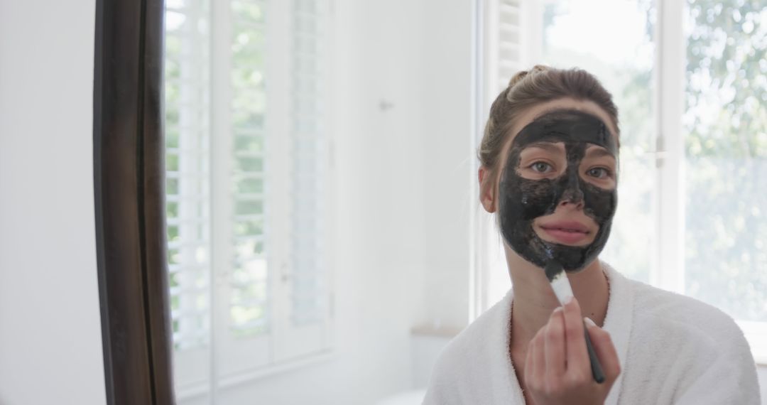 Woman Applying Charcoal Face Mask in Spa-like Setting - Free Images, Stock Photos and Pictures on Pikwizard.com