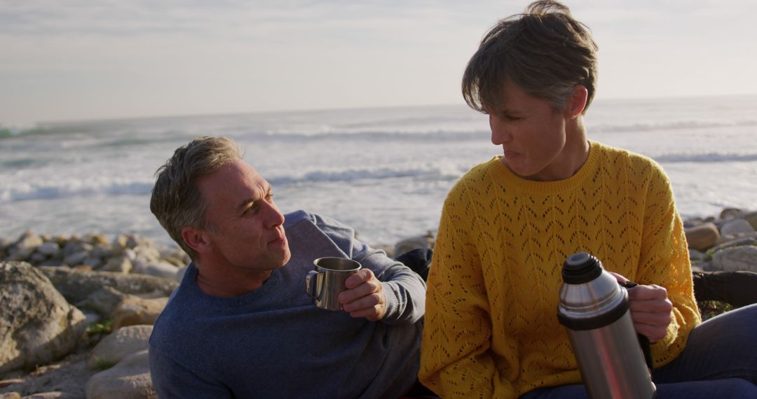 Couple Enjoying Hot Drinks Together at the Beach - Free Images, Stock Photos and Pictures on Pikwizard.com