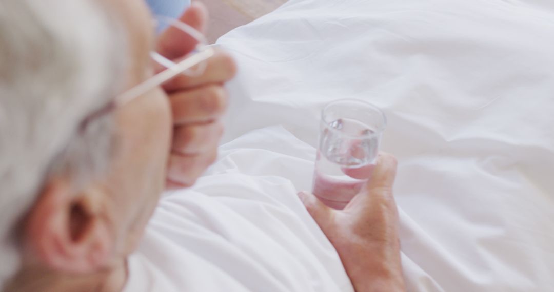 Elderly person drinking water while lying in bed - Free Images, Stock Photos and Pictures on Pikwizard.com