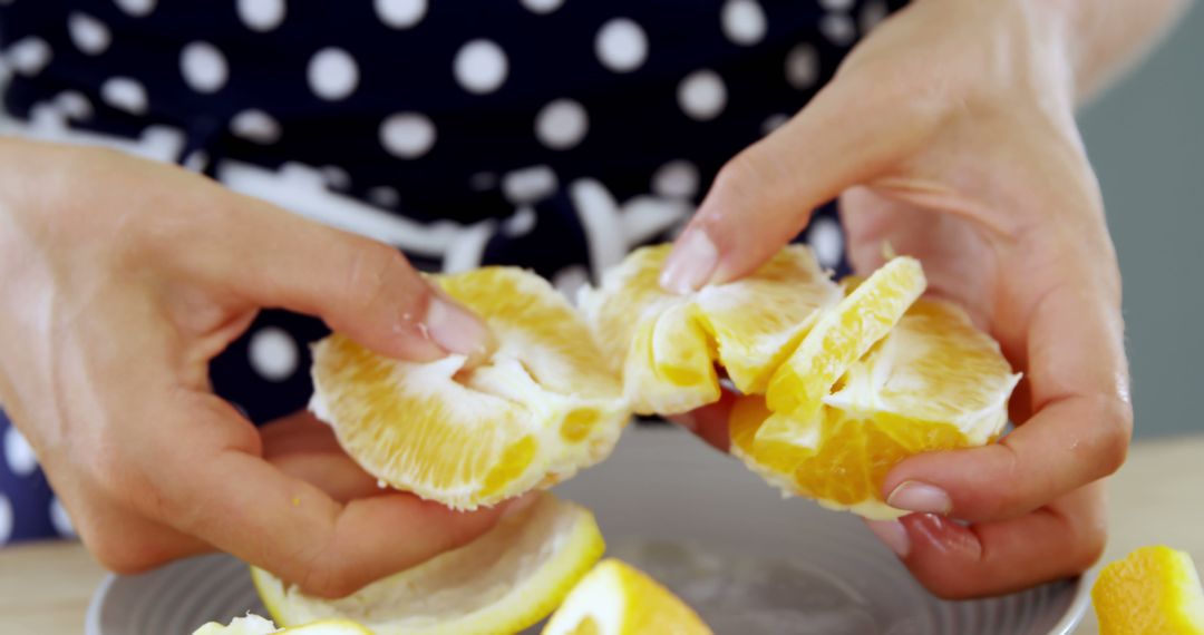 Close-up of hands peeling fresh orange segments with polka dot dress background - Free Images, Stock Photos and Pictures on Pikwizard.com