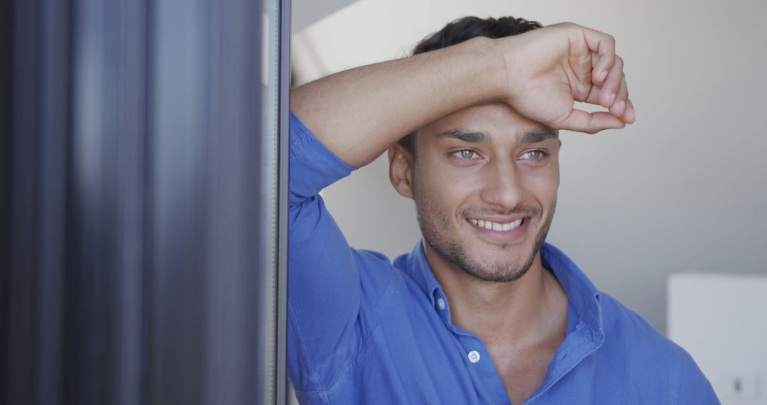 Smiling Man in Blue Shirt Leaning Against Window - Free Images, Stock Photos and Pictures on Pikwizard.com