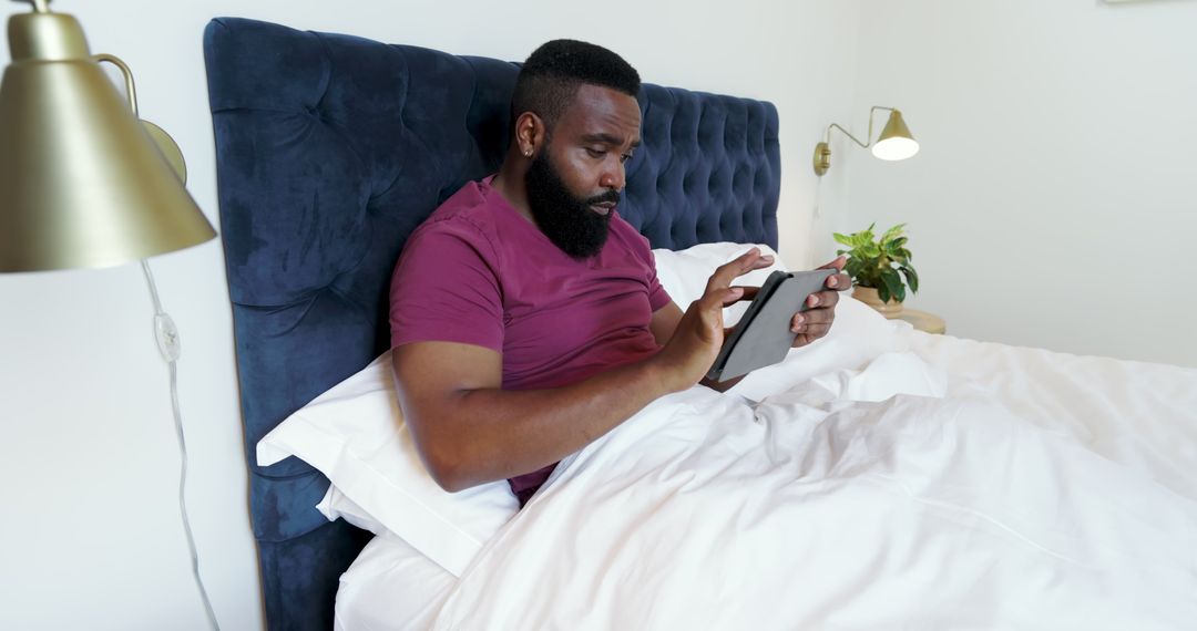 Man Relaxing in Bed Using Tablet in Minimalist Bedroom