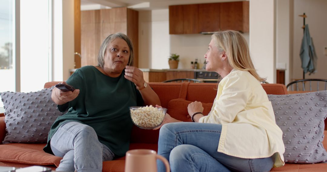 Diverse Female Friends Enjoying Popcorn and Conversation on Modern Sofa