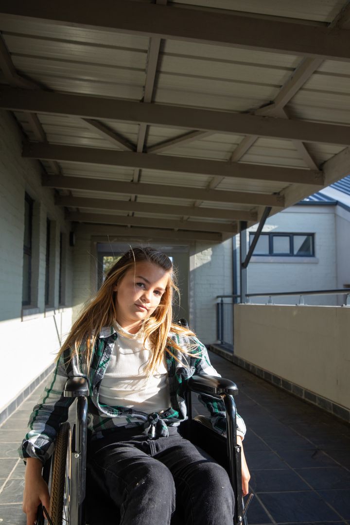 Determined Girl in Wheelchair Navigating Corridor