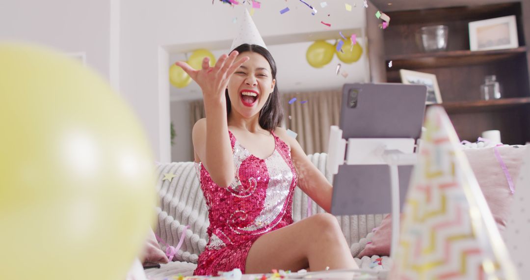 Image of smiling biracial woman throwing confetti in party hat and dressed in pink dress - Free Images, Stock Photos and Pictures on Pikwizard.com