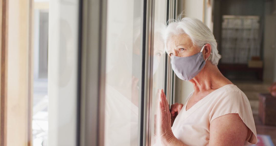 Senior Woman with Protective Mask Looking Out Window Thoughtfully - Free Images, Stock Photos and Pictures on Pikwizard.com