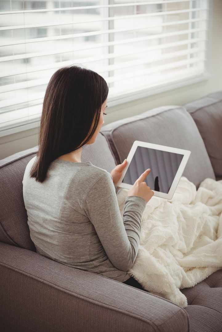 Woman Using Tablet on Sofa in Living Room - Free Images, Stock Photos and Pictures on Pikwizard.com