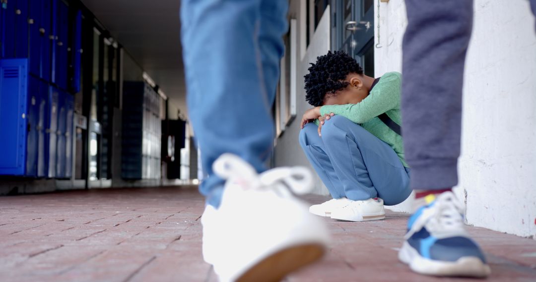 Child Sitting Sadly in School Hallway with Peers Passing By