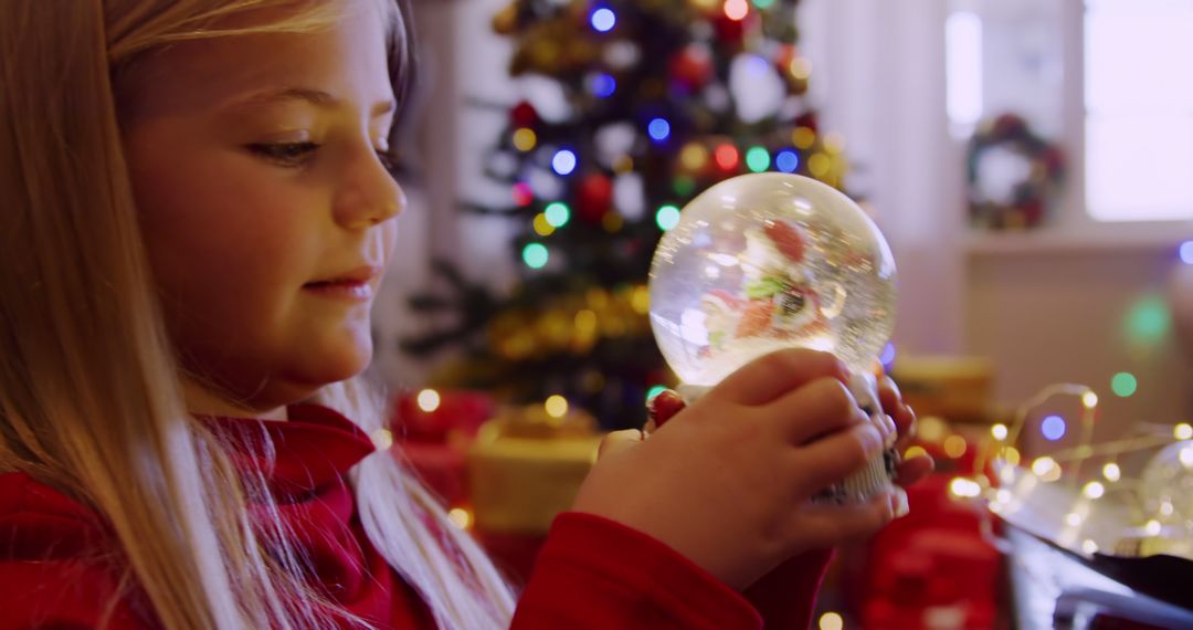 Young Girl Holding Snow Globe During Christmas Celebration - Free Images, Stock Photos and Pictures on Pikwizard.com