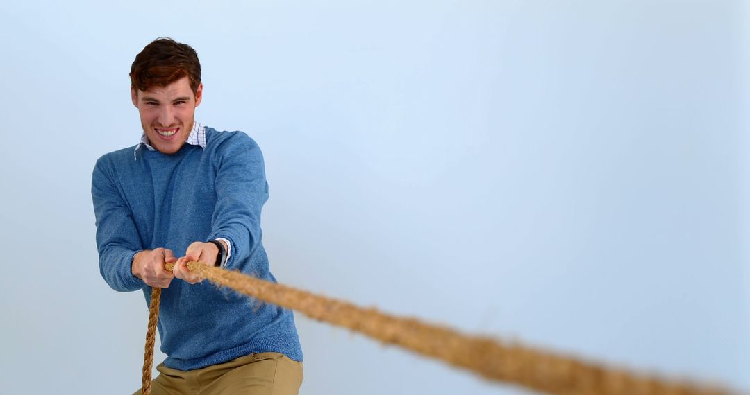 Man Pulling Rope with Determination Wearing Blue Sweater - Free Images, Stock Photos and Pictures on Pikwizard.com