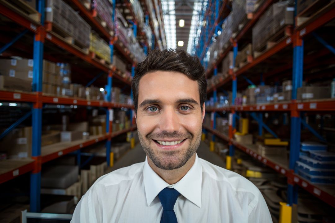 Confident Warehouse Manager Smiling in Organized Inventory Aisle