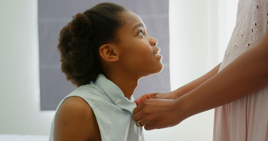Mother Assisting Daughter with Attire in Warm Home Environment