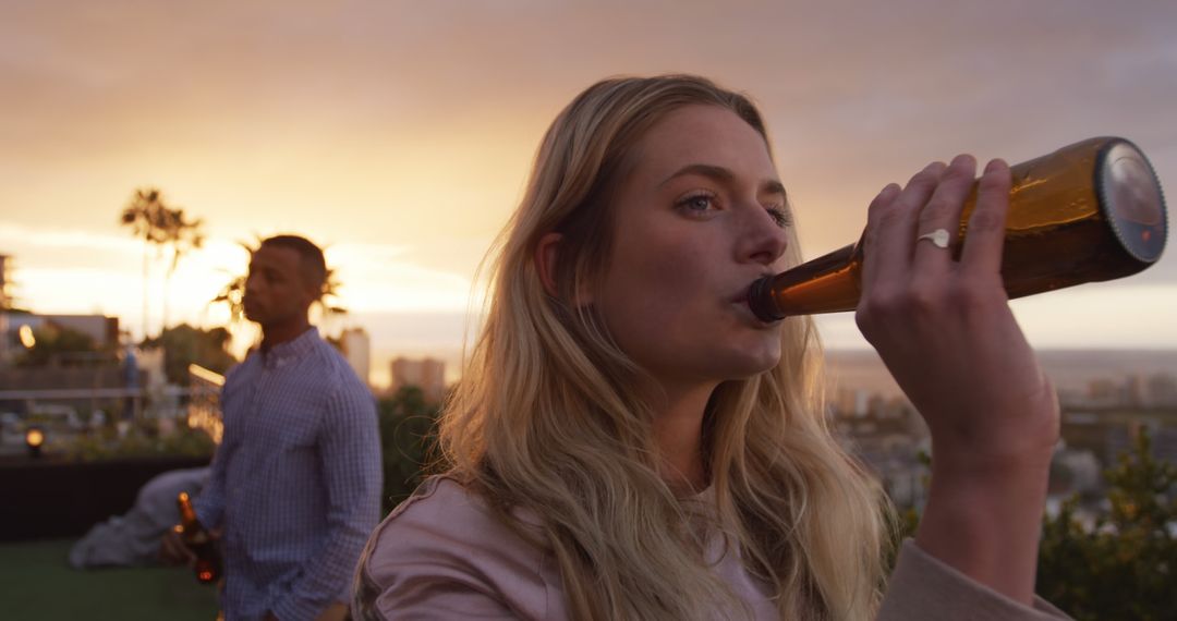 Woman Enjoying Beer at Rooftop Sunset Party - Free Images, Stock Photos and Pictures on Pikwizard.com