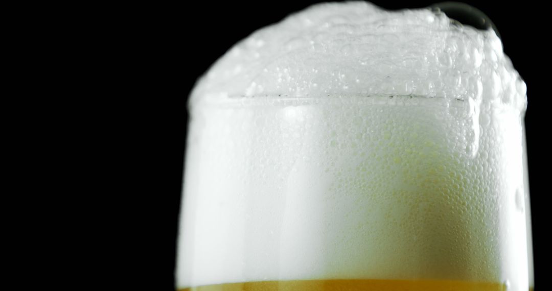 Close-up of Frothy Beer with Foam Overflowing in Glass Against Black Background - Free Images, Stock Photos and Pictures on Pikwizard.com