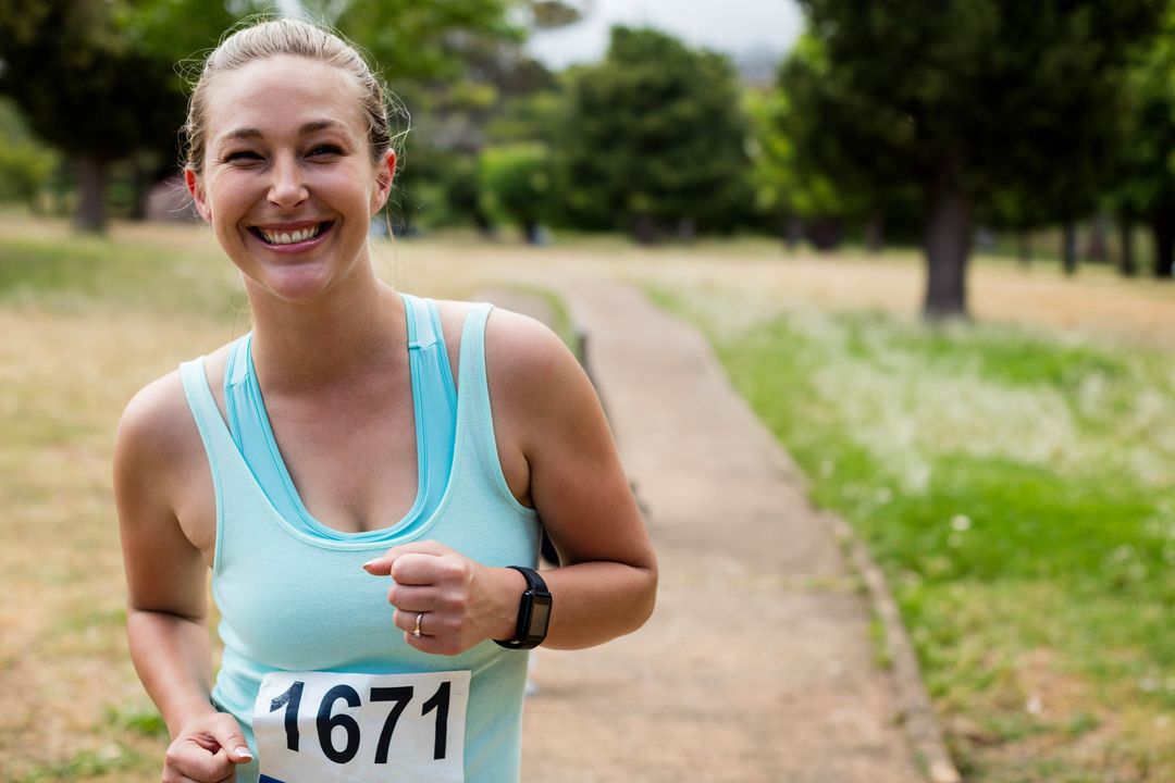 Smiling Woman Running with Race Bib in Park